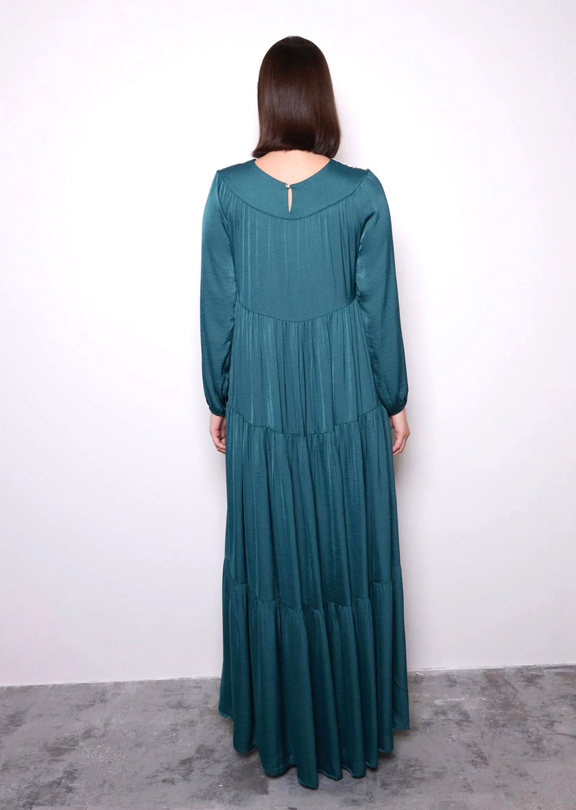 Woman wearing a teal long-sleeve dress against a white background