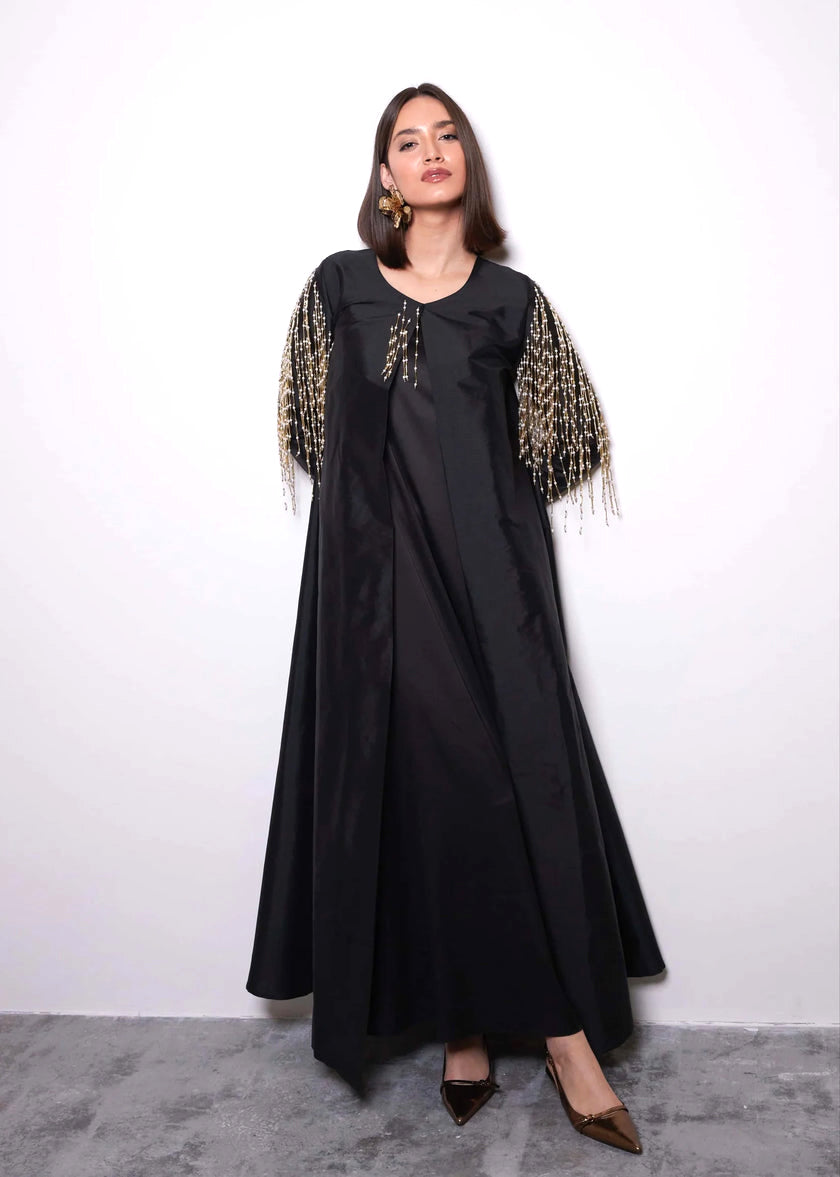 Woman wearing a black dress with decorative sleeves against a white background