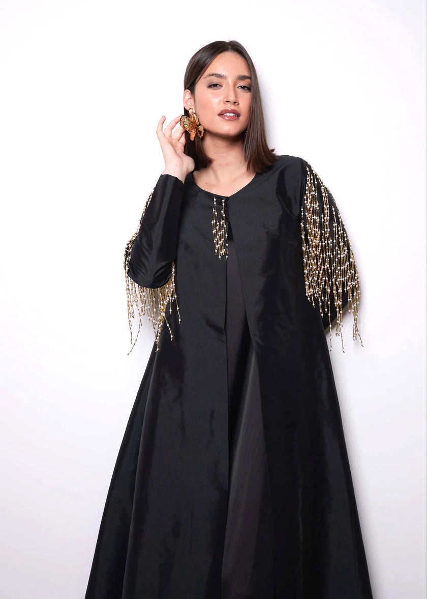 Woman wearing a black dress with gold embellishments on a white background