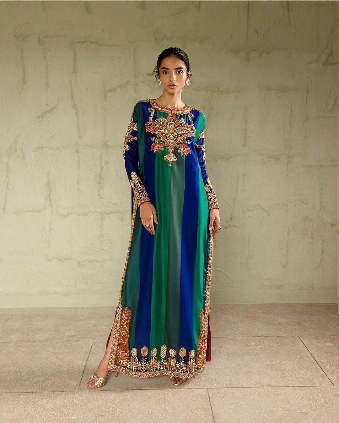 Woman wearing a long, colorful dress with intricate patterns against a neutral background