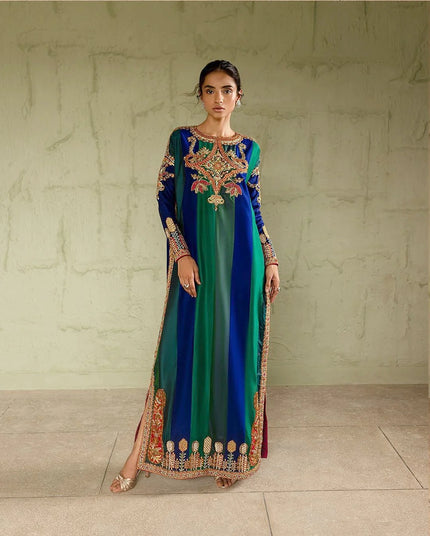 Woman wearing a long, colorful dress with intricate patterns against a neutral background