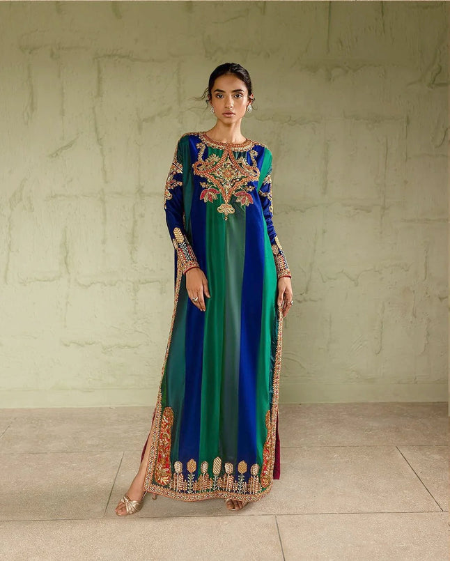 Woman wearing a long, colorful dress with intricate patterns against a neutral background