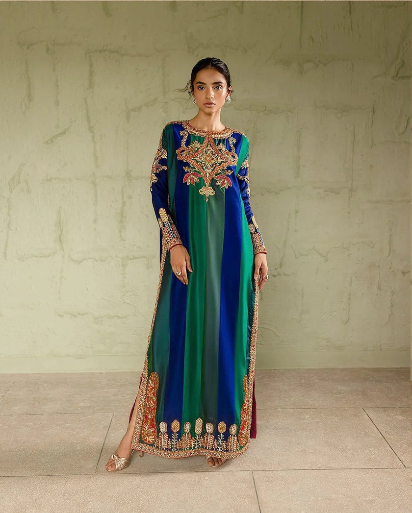 Woman wearing a long, colorful dress with intricate patterns against a neutral background