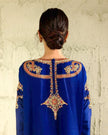 Blue embroidered garment with gold detailing on a textured wall background